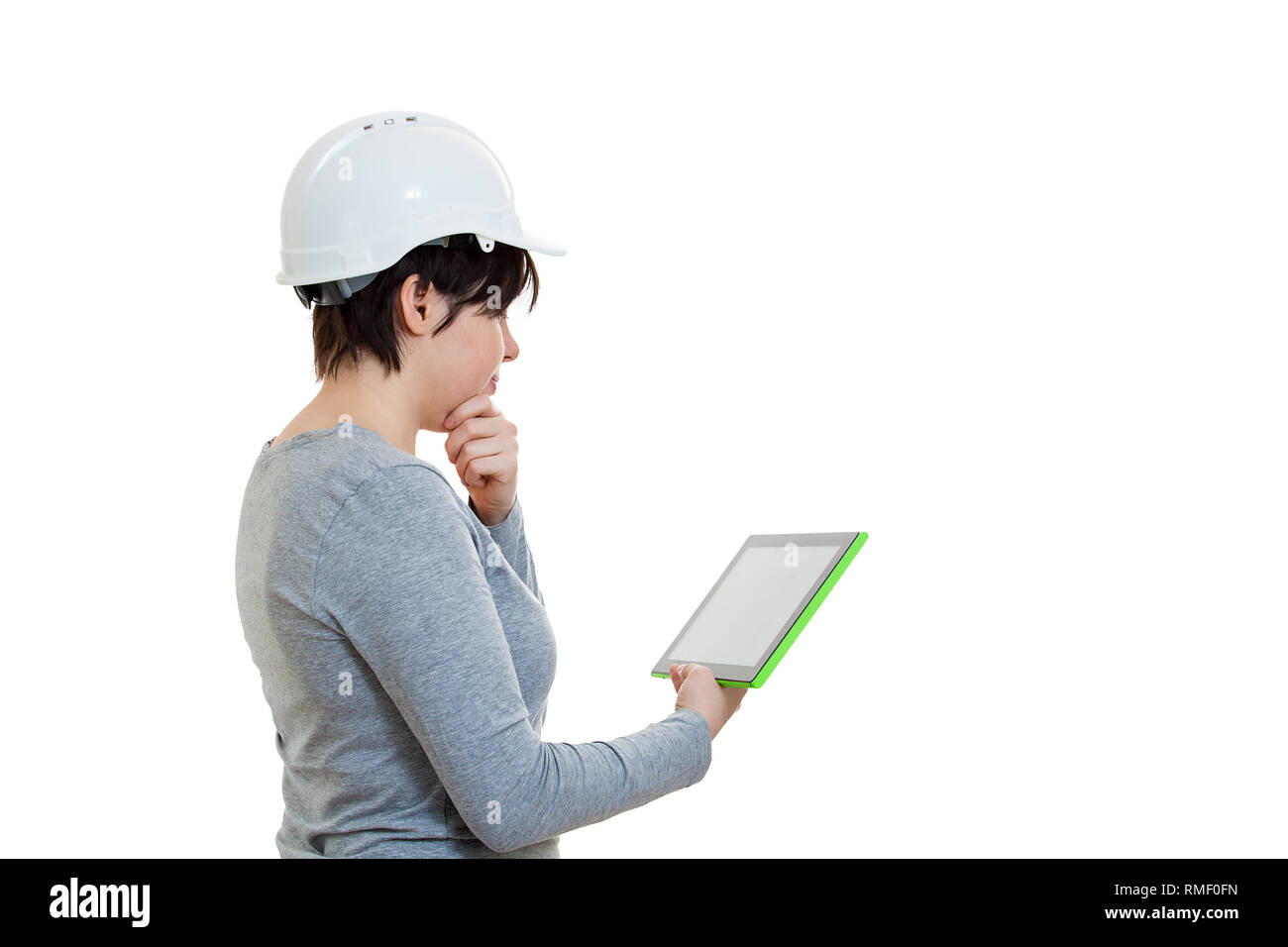 Seitenansicht nachdenklich der jungen Frau Ingenieur tragen Schutzhelm mit einem Tablet Computer Gadget auf weißem Hintergrund berechnen. Stockfoto