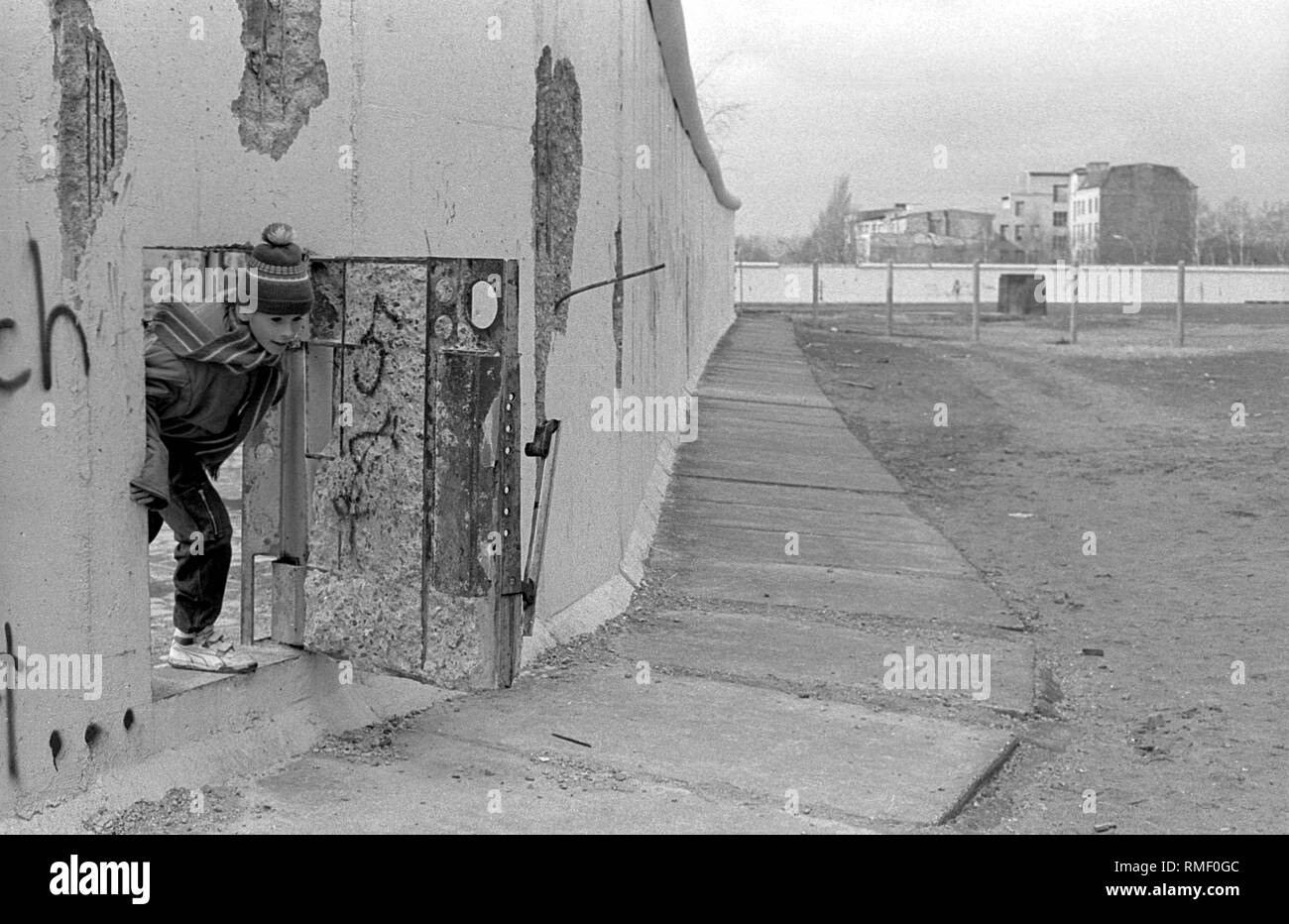 Deutschland, Berlin, 26. Februar 1990: ein Kind durch eine Tür in der Wand, Berliner Mauer am Potsdamer Platz, (Weinhaus Hütte). Stockfoto