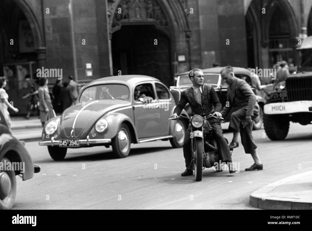 Viel befahrenen Straße Verkehr auf dem Marienplatz in der Münchner Innenstadt. Das Bild zeigt einen VW-Käfer, und zwei Männer auf einem Motorrad. Stockfoto