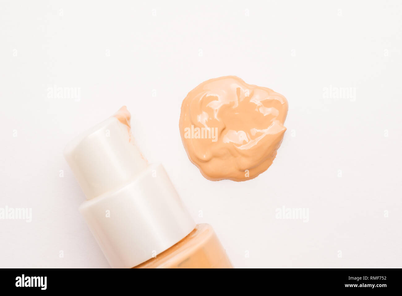 Hellbeige liquid concealer und Sahne bestreichen auf weißem Hintergrund. Selektiver Fokus Stockfoto