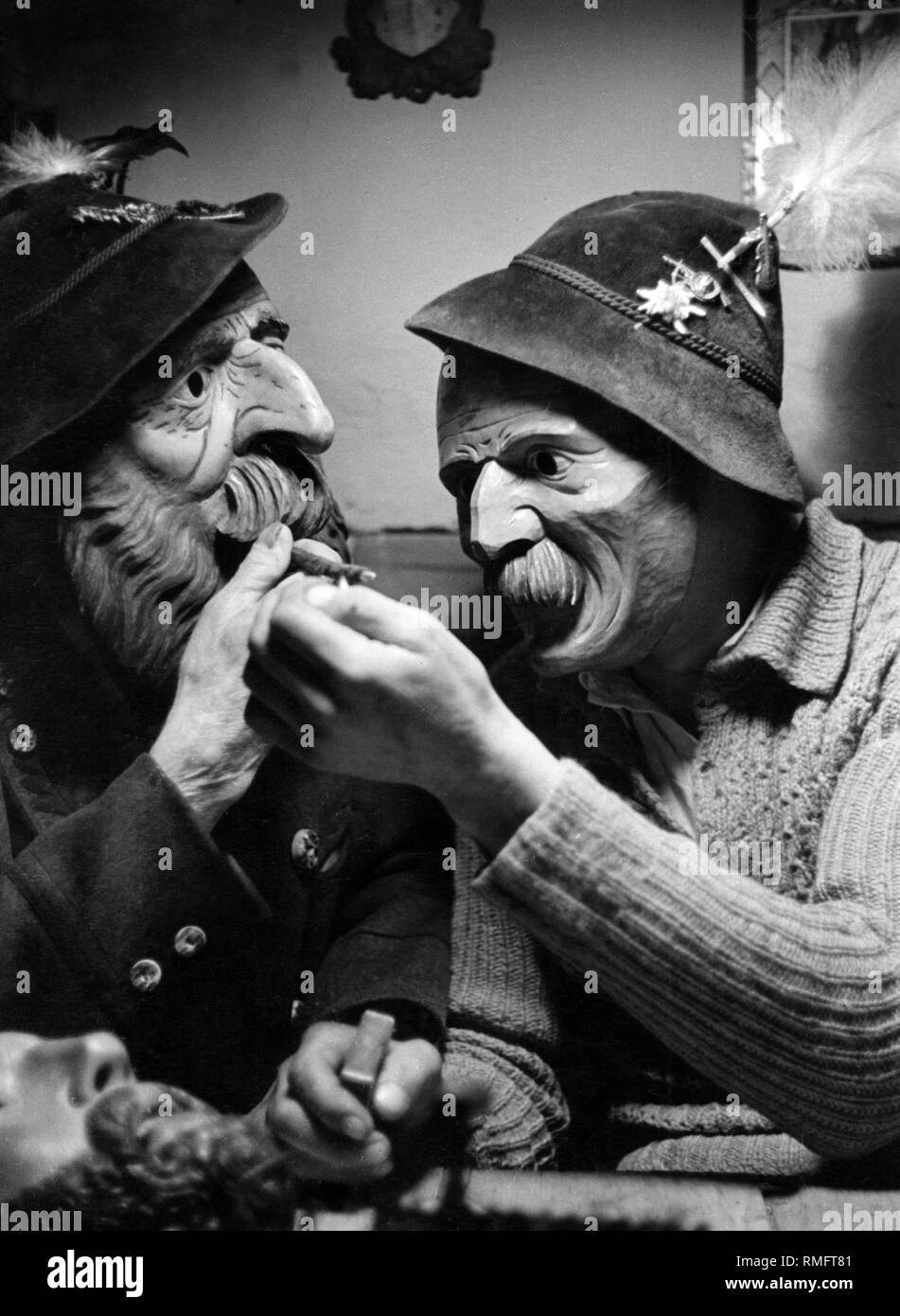 Zwei Männer in Tracht tragen alte Werdenfelser geschnitzte Masken. Stockfoto
