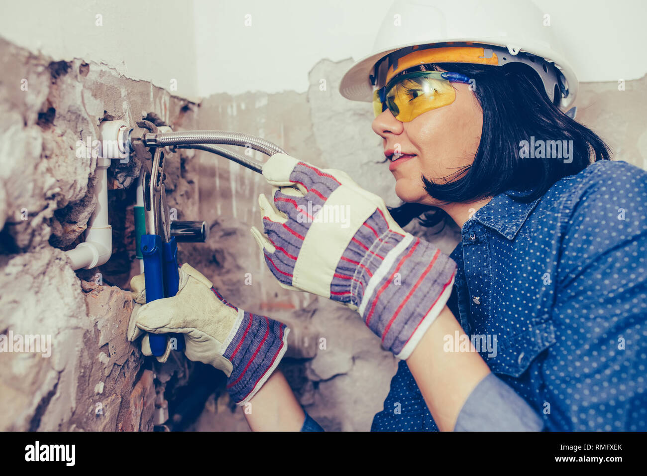 Nahaufnahme der weiblichen Klempner in Handschuhe mit Drehmomentschlüssel Reparaturen die Rohre im Bad. Reparatur von Rohrleitungen, Ventile, Wasser m. Stockfoto