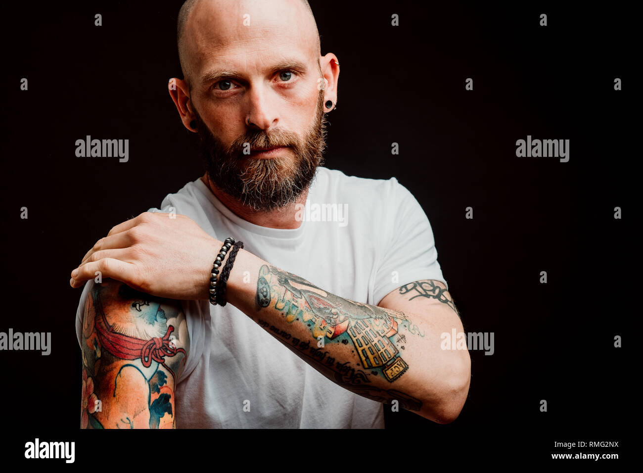 Unbehaarte Hipster in t-shirt, bärtigen Tattoos auf Händen auf schwarzem Hintergrund Stockfoto