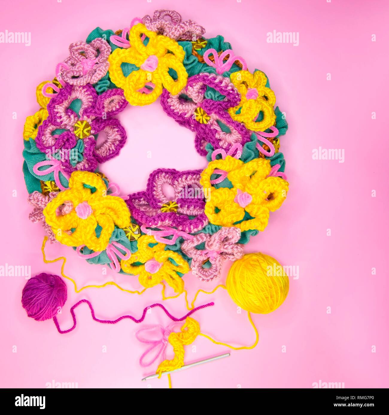 Frühling basteln Idee tun woolen Kranz. Wolle Garn gehäkelte freie Form Blume Dekoration mit Garn Gewinde auf der rosa Hintergrund Stockfoto