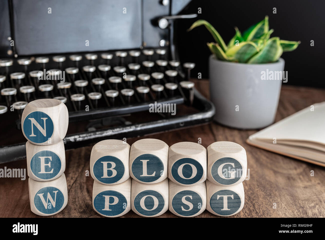 Worte neuen Blog-eintrag auf Holzklötzen gegen vintage Schreibmaschine, Topfpflanzen und Notizen auf dem Tisch. Stockfoto