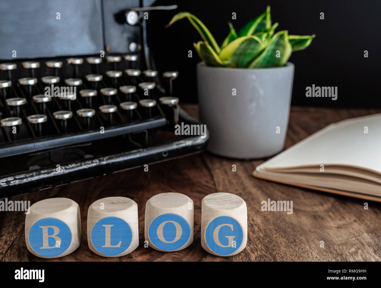 Wort Blog auf Holzklötzen gegen vintage Schreibmaschine, Topfpflanzen und Notizen auf dem Tisch Stockfoto