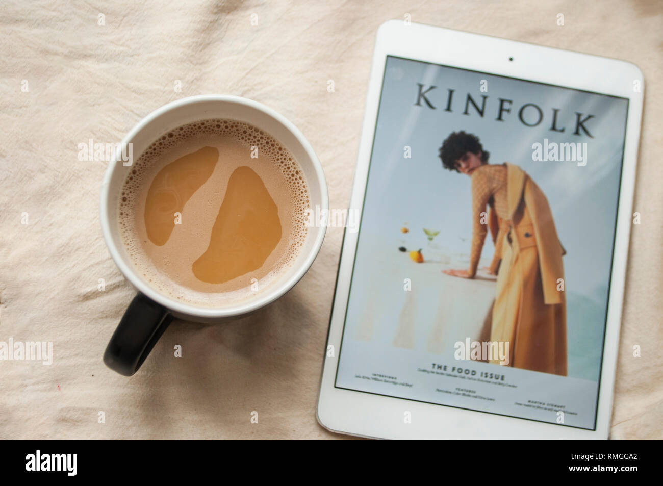 Morgendliche routine Konzept. Eine Tasse Kaffee und Tablet mit Kinfolk Magazin. Stockfoto