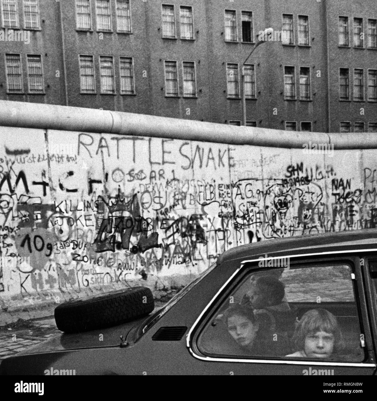 Blick über die Berliner Mauer im Osten von Berlin, im Vordergrund sind Kinder im Auto. Stockfoto