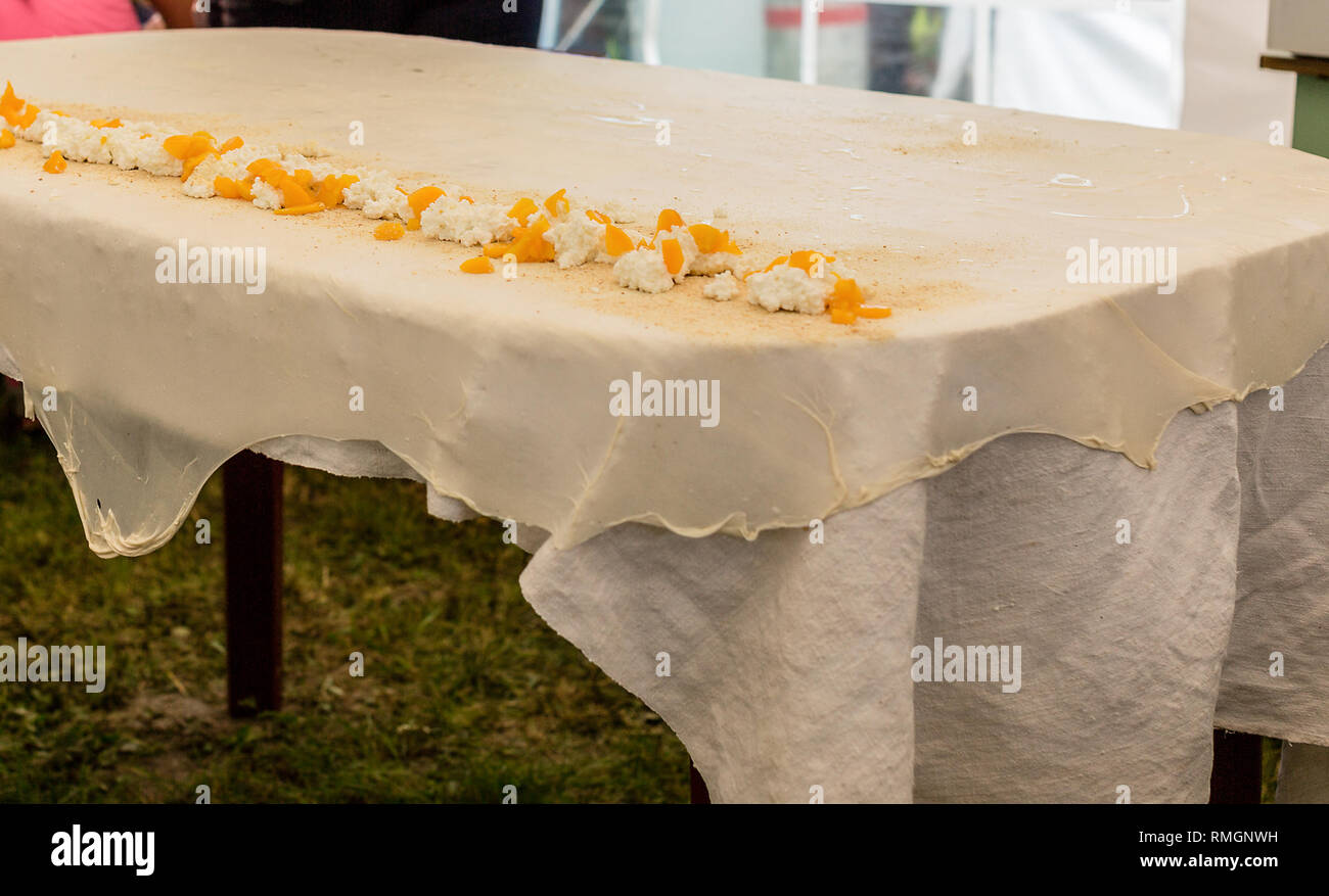 Hausgemachte Strudel Teig auf einer traditionellen Bettwäsche Tischdecke bereit für die Herstellung von Quark Kuchen und anderen Backwaren. Zutaten für die Füllung - Ferienhaus ch Stockfoto