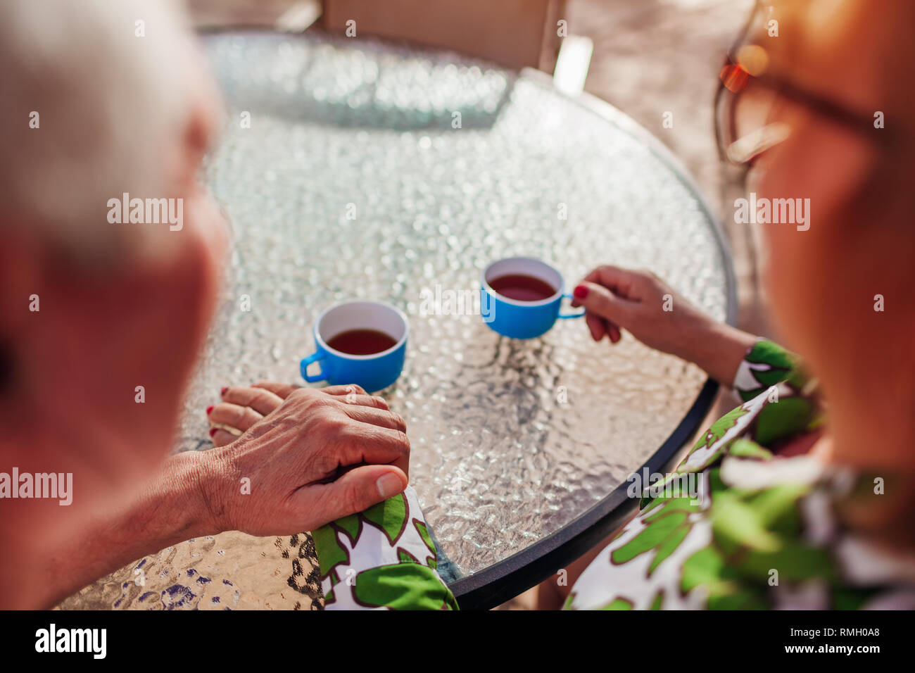 Senior paar Tee trinken im Hotel Cafe halten sich an den Händen. Glückliche Menschen genießen Urlaub. Close-up Stockfoto Senior paar Tee trinken im Hotel Cafe halten sich an den Händen. Glückliche Menschen genießen Urlaub. Close-up Stockfoto