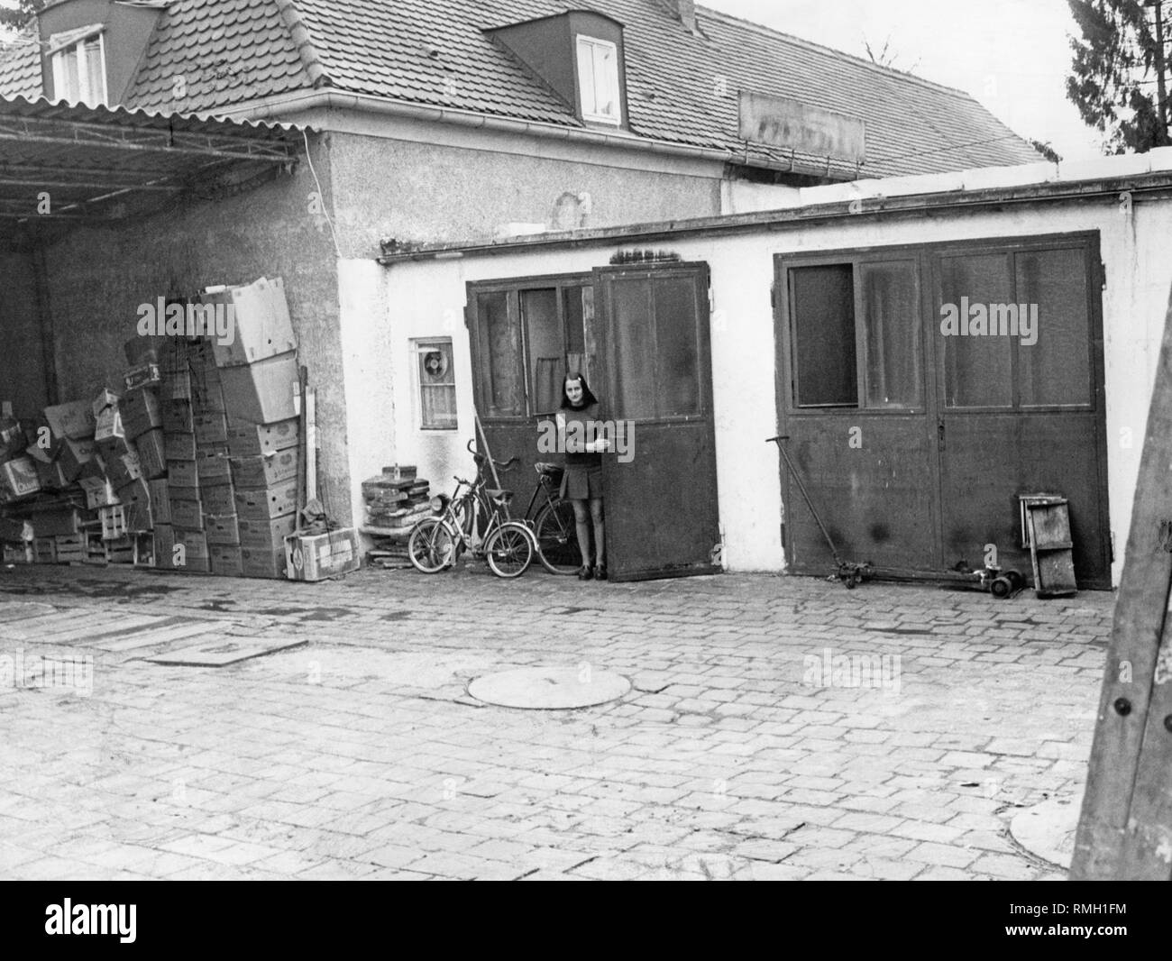 Anzeigen eines Wohnhauses (wahrscheinlich in München), wo Gastarbeiter leben. Vor der Garage neben einem Kinder Fahrrad ist ein Mädchen. Stockfoto