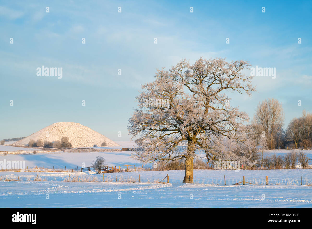 Frosted Eiche vor Silbury Hill im Winter Schnee bei Sonnenaufgang. Avebury, Wiltshire, England Stockfoto
