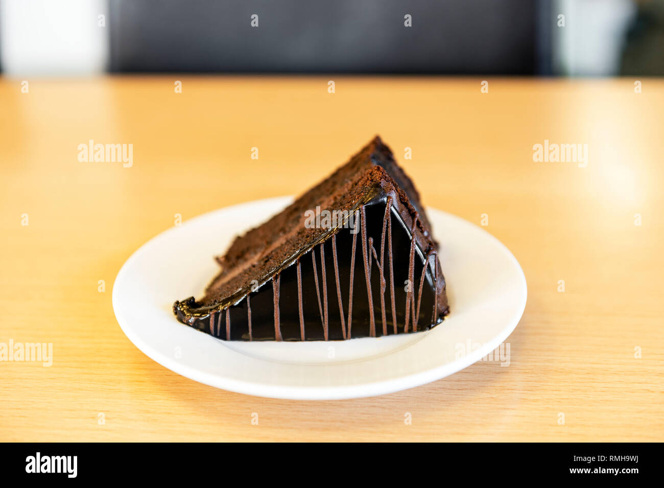 Ein Stück Schokolade Kuchen mit Puderzucker auf einem weißen Teller auf einem Büro Schreibtisch, Großbritannien serviert. Stockfoto
