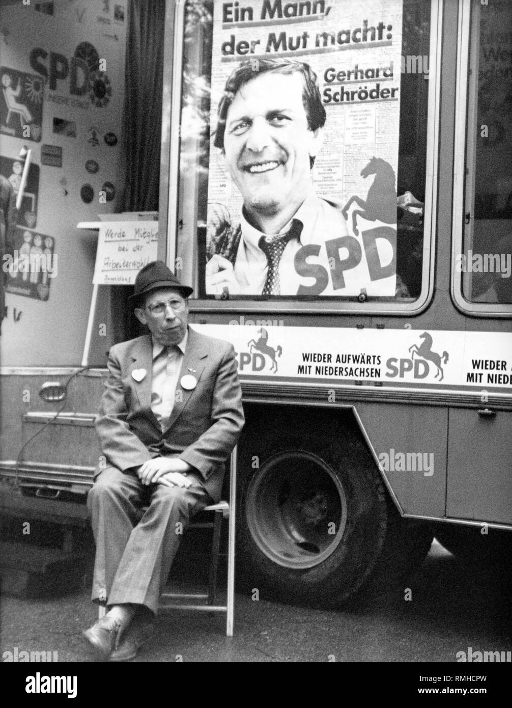 Ein Mitkämpfer wartet vor der Kampagne Bus für SPD-Spitzenkandidat Gerhard Schroeder. Auf dem Bus ist ein Plakat mit dem Portrait von Gerhard Schroeder und das Sprichwort: "ein Mann, der stärkt: Gerhard Schroeder'. Stockfoto
