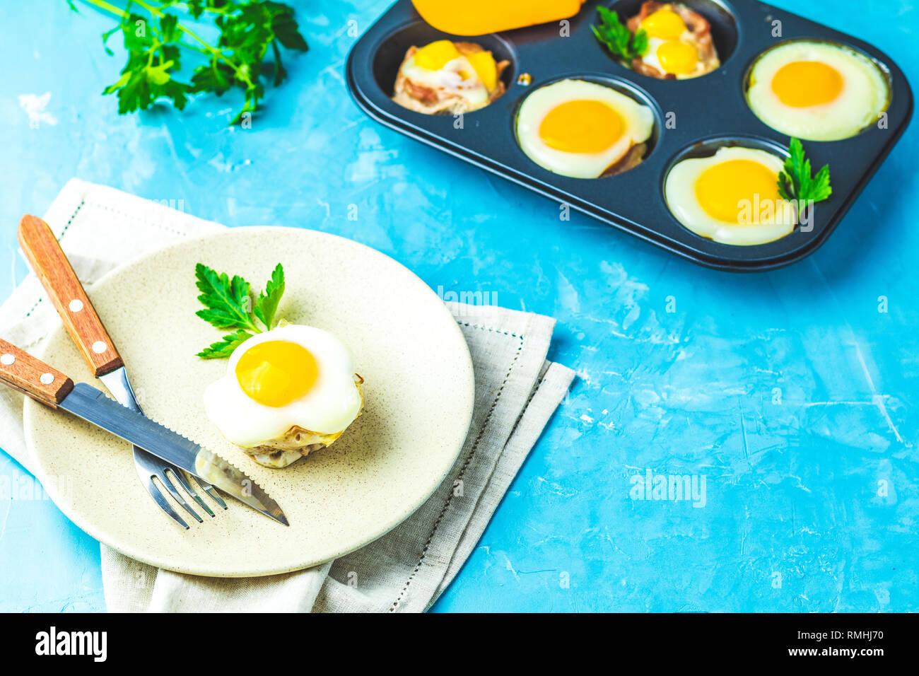 Gebackene Eier in der Licht- und Backformen. Portioniert Auflauf von Speck und Eier im italienischen Stil. Blauer Beton Tischfläche Hintergrund. Stockfoto
