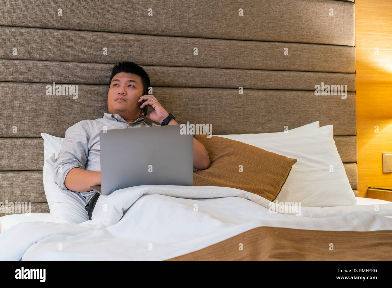 Asiatische Geschäftsmann mit Telefon im Hotelzimmer Stockfoto