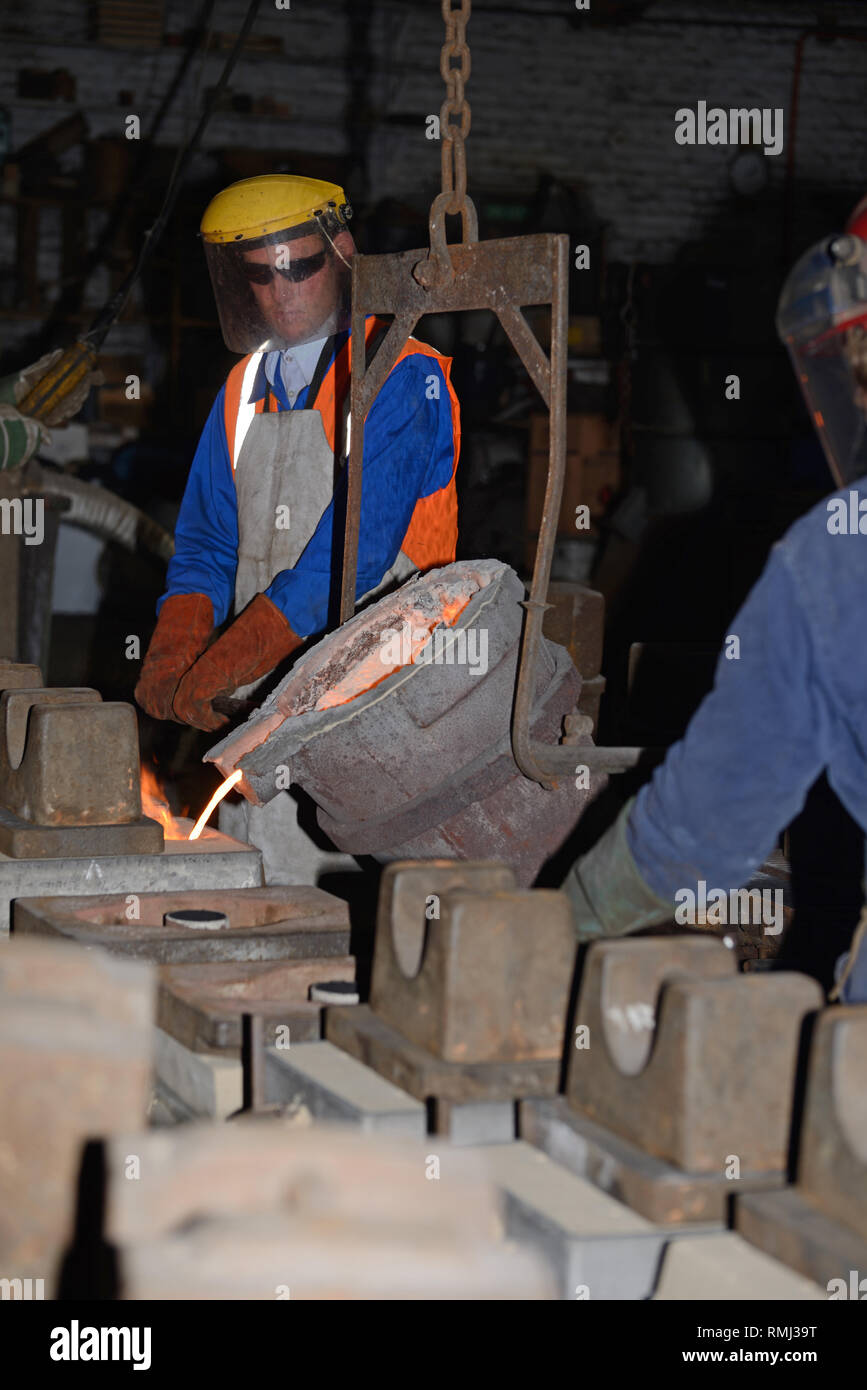 Gießer geschmolzenes Eisen in Formen für die Herstellung von Gitterrosten Feuer gießen Stockfoto