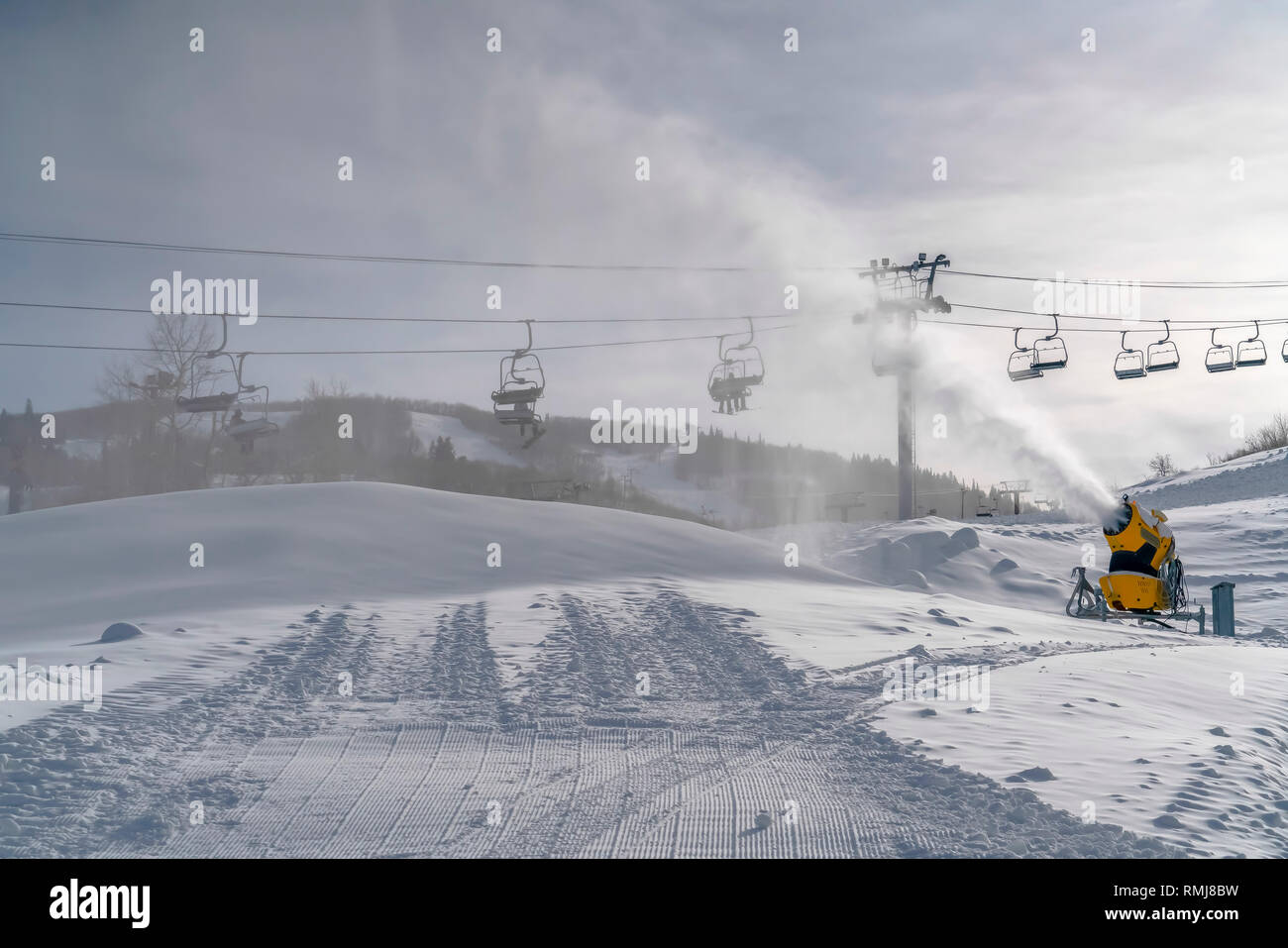Skilifte über Schneekanonen und sonnigen verschneiten Berg Stockfoto