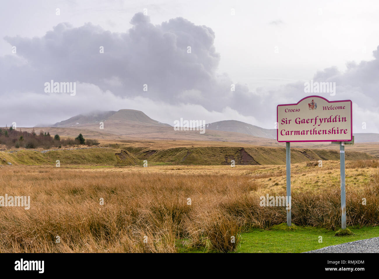 „Welcome to Carmarthenshire“-Schild mit Cumulonimbus-Wolken, die über den Black Mountains (Carmarthen-Fans) in den Brecon Beacons, Wales, Großbritannien hängen Stockfoto