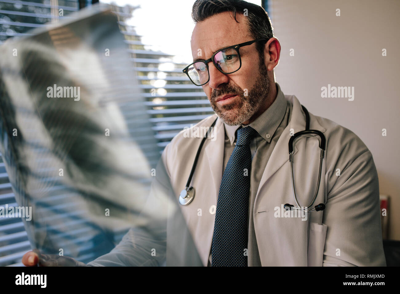 Betroffenen männlichen Arzt auf Brust x-ray in seinem Büro. Arzt suchen von Scan, X-ray von Patienten in den Lungen. Stockfoto