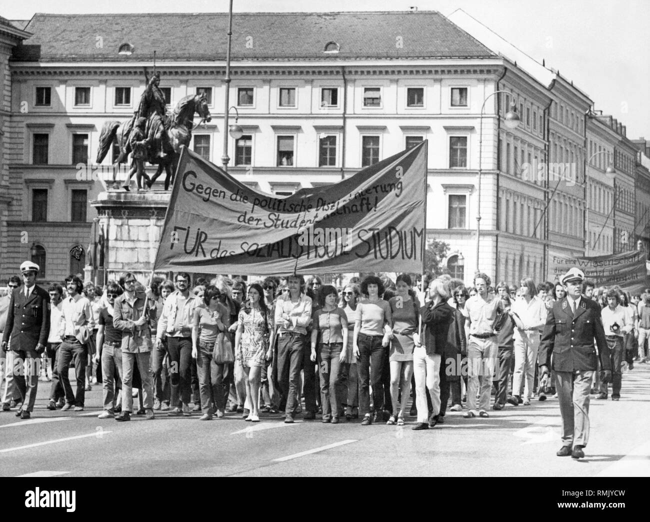 Studenten demonstrieren in München, einem Banner lautet: "Gegen die politische Disziplinierung-Stiftung! Für das sozialistische Studium' ('Gegen die politische Disziplinierung der Studenten! Zugunsten der sozialistischen Studien"). Im Hintergrund die Statue von Ludwig dem Bayern. Stockfoto