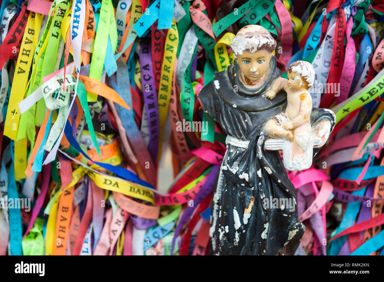 Eine beschädigte Statue mit dem Baby Jesus steht unter farbenfrohe Brasilianische wünschen Bänder an der berühmten Kirche Bonfim in Salvador, Bahia, Brasilien Stockfoto