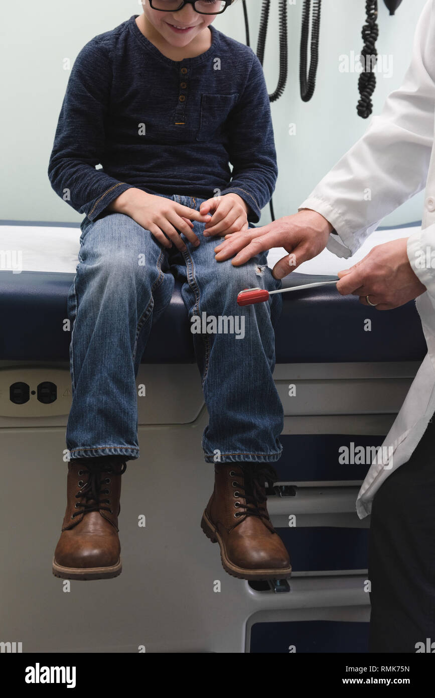 Jungen asiatischen männlicher Arzt Prüfung der kaukasischen jungen Patienten Knie in einer Klinik. Männlicher Arzt mit Reflex h Stockfoto