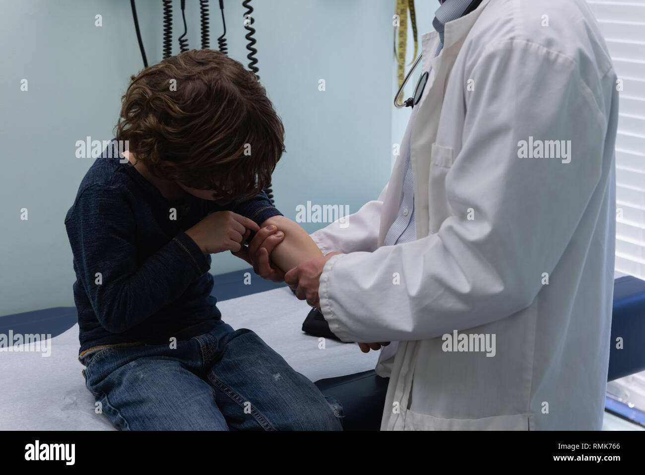 Jungen asiatischen männlicher Arzt Kontrolle Blutdruck der kaukasischen jungen Patienten in der Klinik Stockfoto