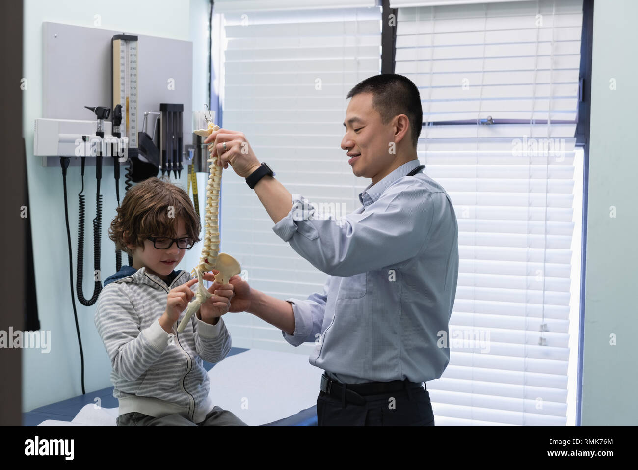Jungen asiatischen männlicher Arzt zeigen Wirbelsäule Modell mit kaukasischen jungen Patienten Stockfoto