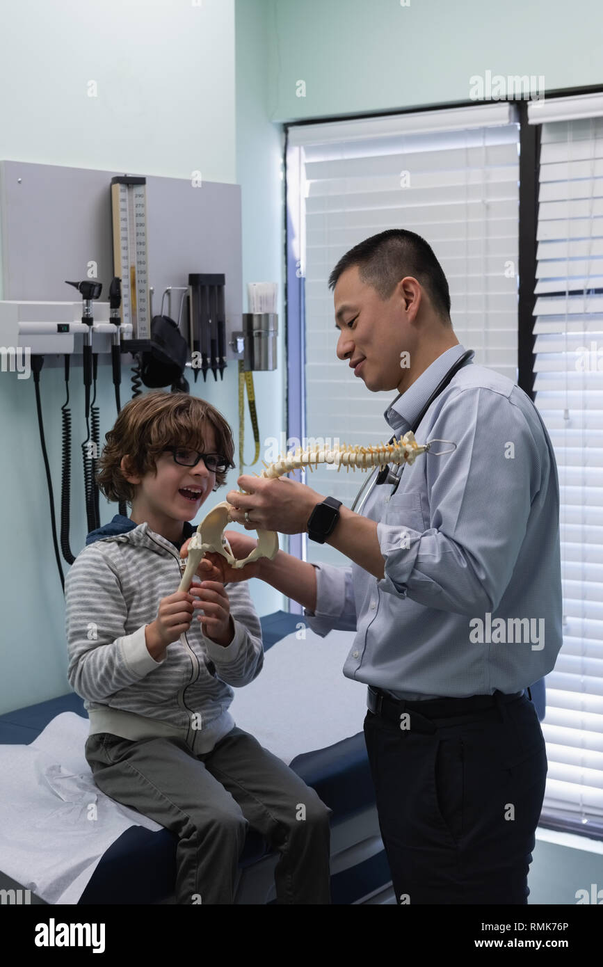 Jungen asiatischen männlicher Arzt zeigen Wirbelsäule Modell mit kaukasischen jungen Patienten Stockfoto