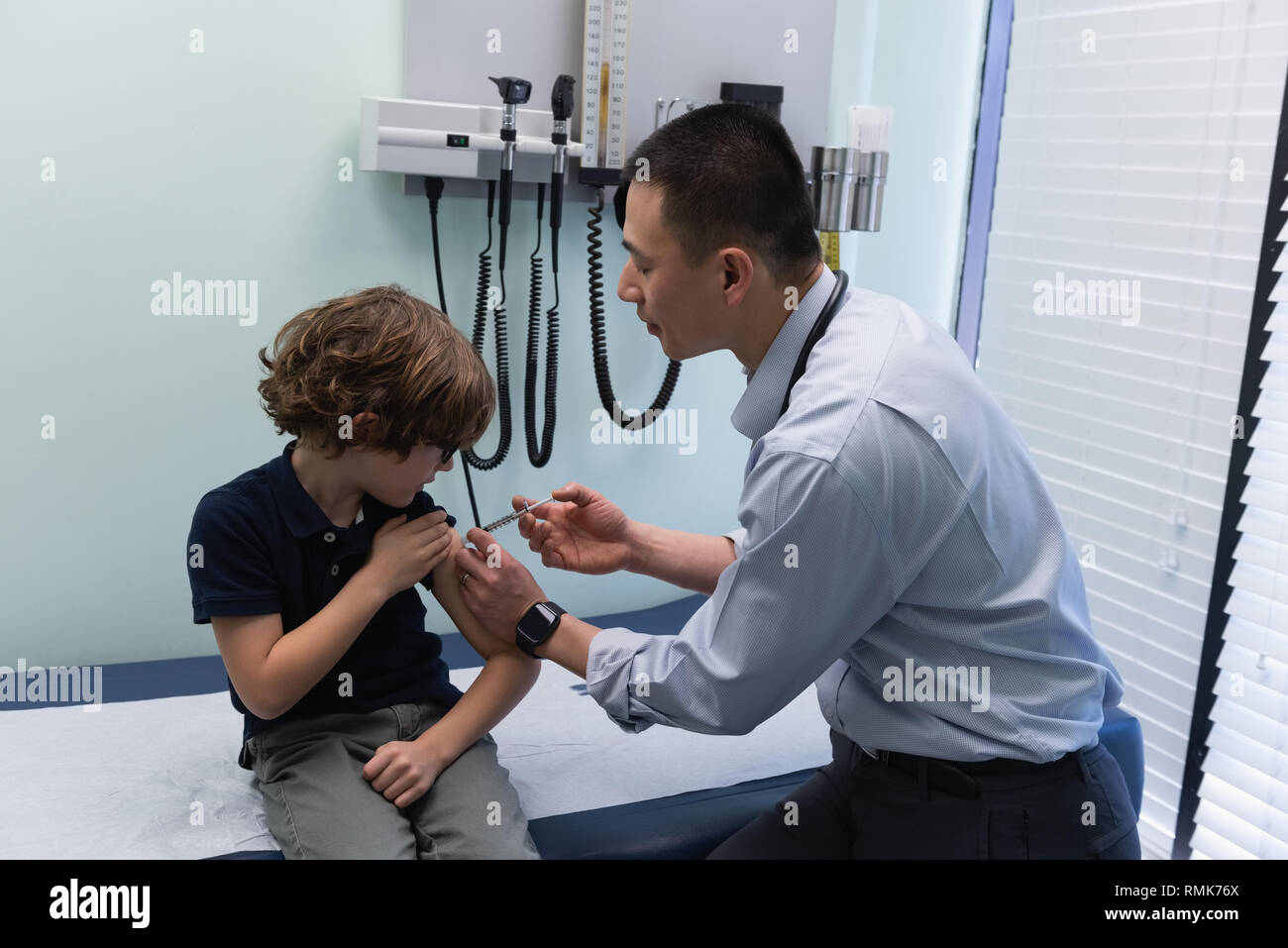 Jungen asiatischen männlicher Arzt spritzen Spritze mit kaukasischen jungen Patienten in der Klinik Stockfoto