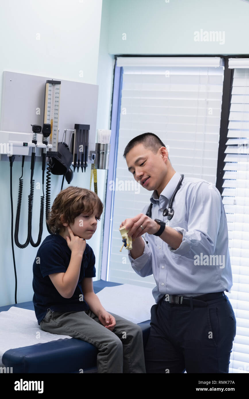 Jungen asiatischen männlicher Arzt zeigt das ear-Modell mit kaukasischen jungen Patienten in der Klinik Stockfoto