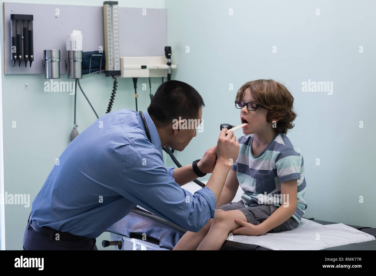 Jungen asiatischen männlicher Arzt Prüfung der kaukasischen junge Patienten mit Werkzeug in einer Klinik Stockfoto