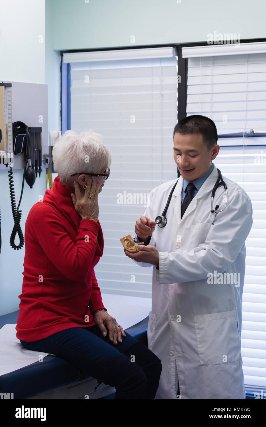 Jungen Asiatischen männlicher Arzt- und älteren Patienten diskutieren über das ear-Modell an der Klinik Stockfoto