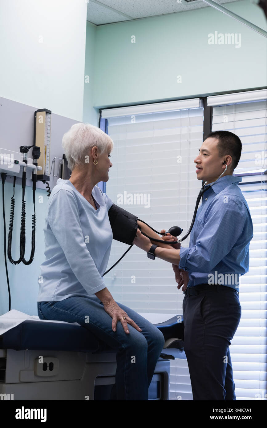 Männlicher Arzt Kontrolle Blutdruck von älteren Patienten Blut Manometer an der Klinik Stockfoto