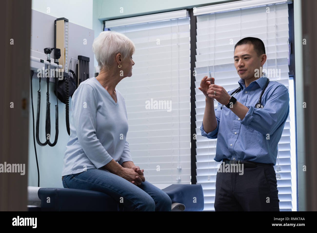 Jungen Asiatischen männlicher Arzt Injektion von älteren Patienten Stockfoto