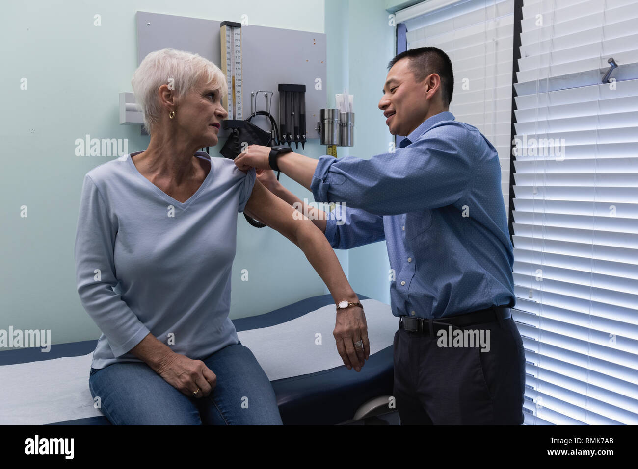 Jungen Asiatischen männlicher Arzt Injektion von älteren Patienten Stockfoto