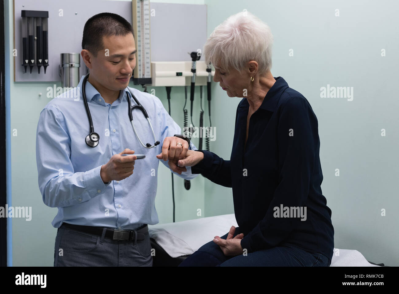 Jungen Asiatischen männlicher Arzt messen Blutzucker mit glucometer der älteren Frau Stockfoto