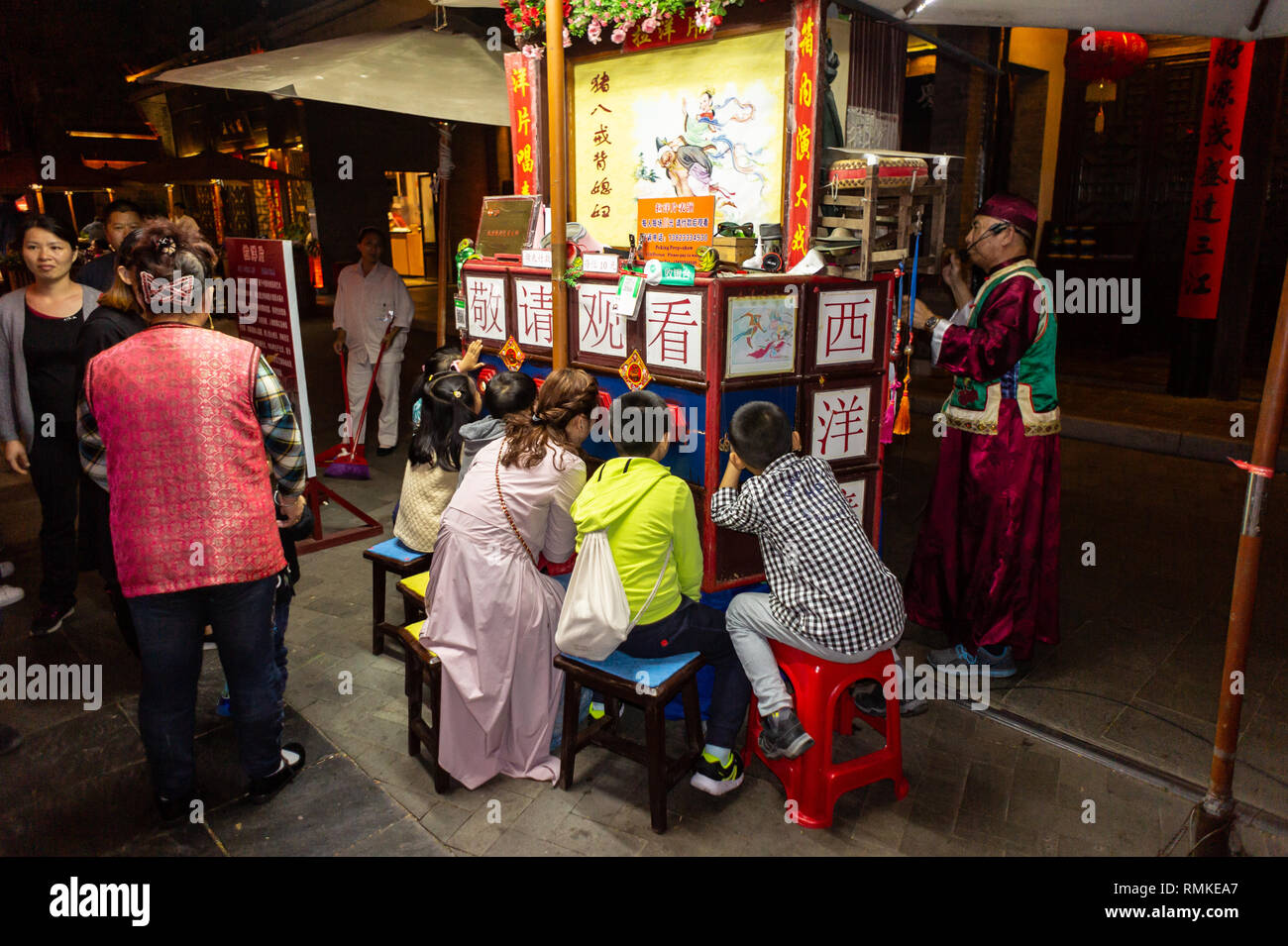 Chinesische Zuschauer verfolgen ein Peking Peep Show in einem Park in Shenzhen, China Stockfoto