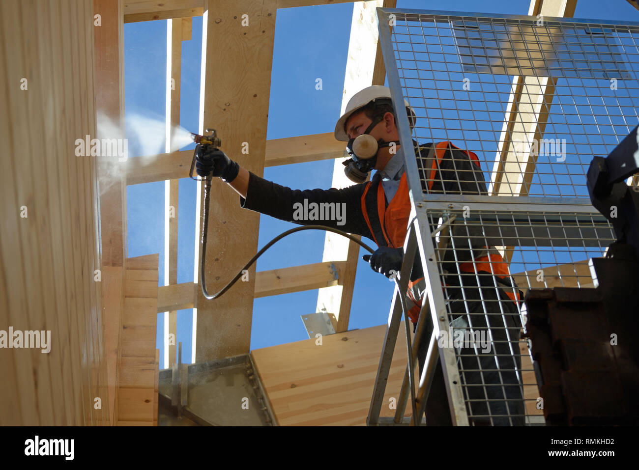 Handwerker Lackierung der Wand eines hölzernen Industriegebäude mit Holz Konservierungsmittel Stockfoto