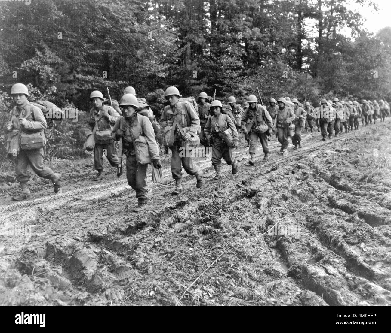 Japanisch-amerikanischen Infanteristen der 442Nd Regimental Combat Team Wanderung auf einen schlammigen Französische Straße im Chambois Sektor, Frankreich, Ende 1944. Stockfoto