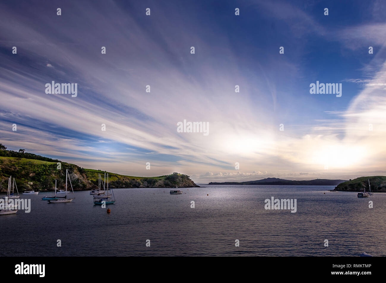 Dramatischer Sonnenuntergang vom Waiheke nach Auckland inter gesehen - Island Fähre. Ruhige Bucht mit Segeln Boote vor Anker, gegen die Wolken mit Hintergrundbeleuchtung Stockfoto