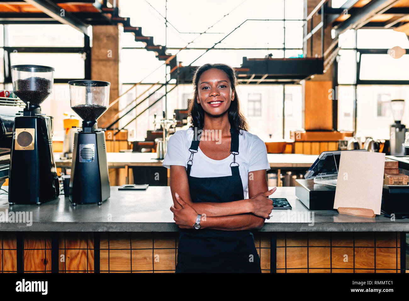 Porträt eines lächelnden Coffee shop besitzer stehen an der Theke tragen Schürze und Arme gekreuzt Stockfoto