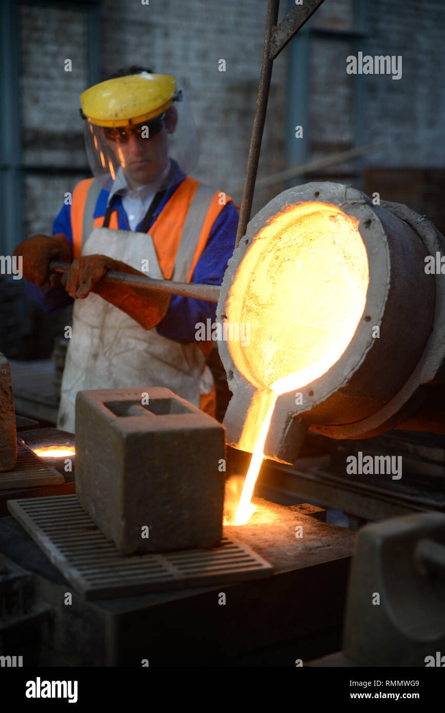 Gießer geschmolzenes Eisen in Formen für die Herstellung von Gitterrosten Feuer gießen. (Bei vorhandenem Licht mit geringen Schärfentiefe erschossen Sie.) Stockfoto