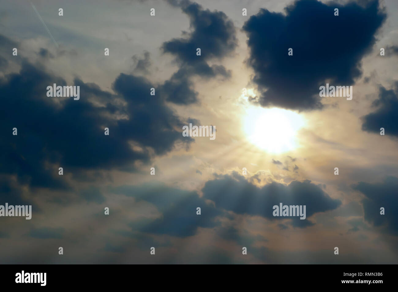 Sonnenstrahlen Strahlen von der Sonne teilweise durch eine Bank von dunklen Wolken stratocumulus Verweilen in den Himmel nach einem Sommer Sturm abgedeckt. Stockfoto
