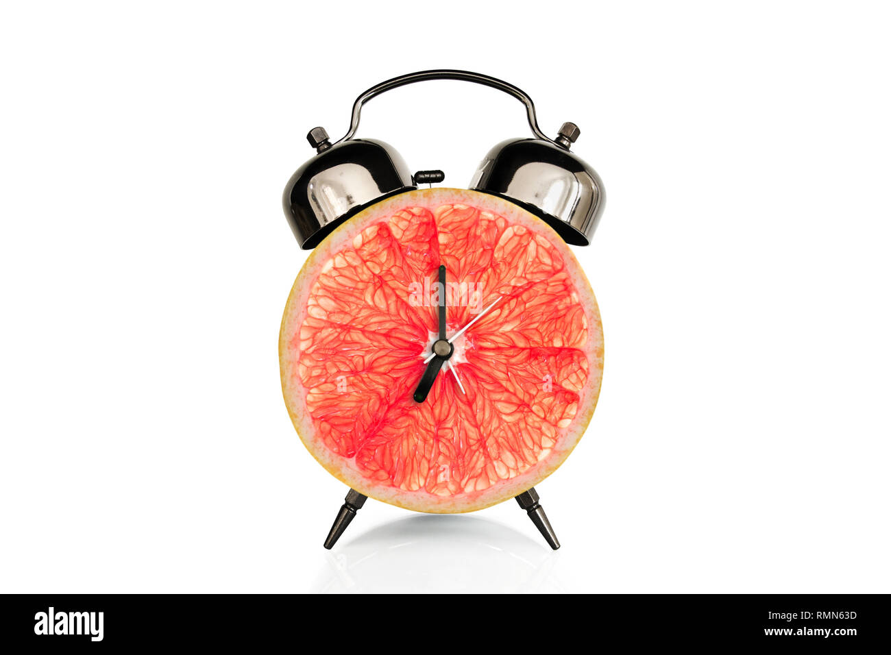 Grapefruiti Slice auf Wecker, auf weißem Hintergrund, Obst und Vitamine Ernährung beim Frühstück Ernährung Konzept isoliert Stockfoto
