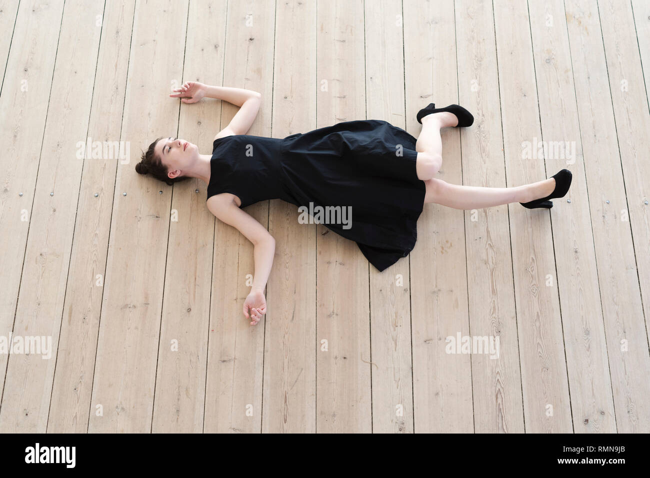 Junge Frau liegt auf Holzboden Stockfoto