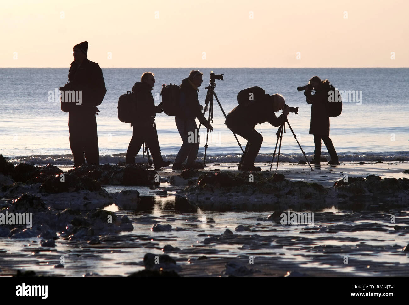 Gruppe von hobbyfotografen Fotografieren der Sonnenuntergang am Strand. Stockfoto