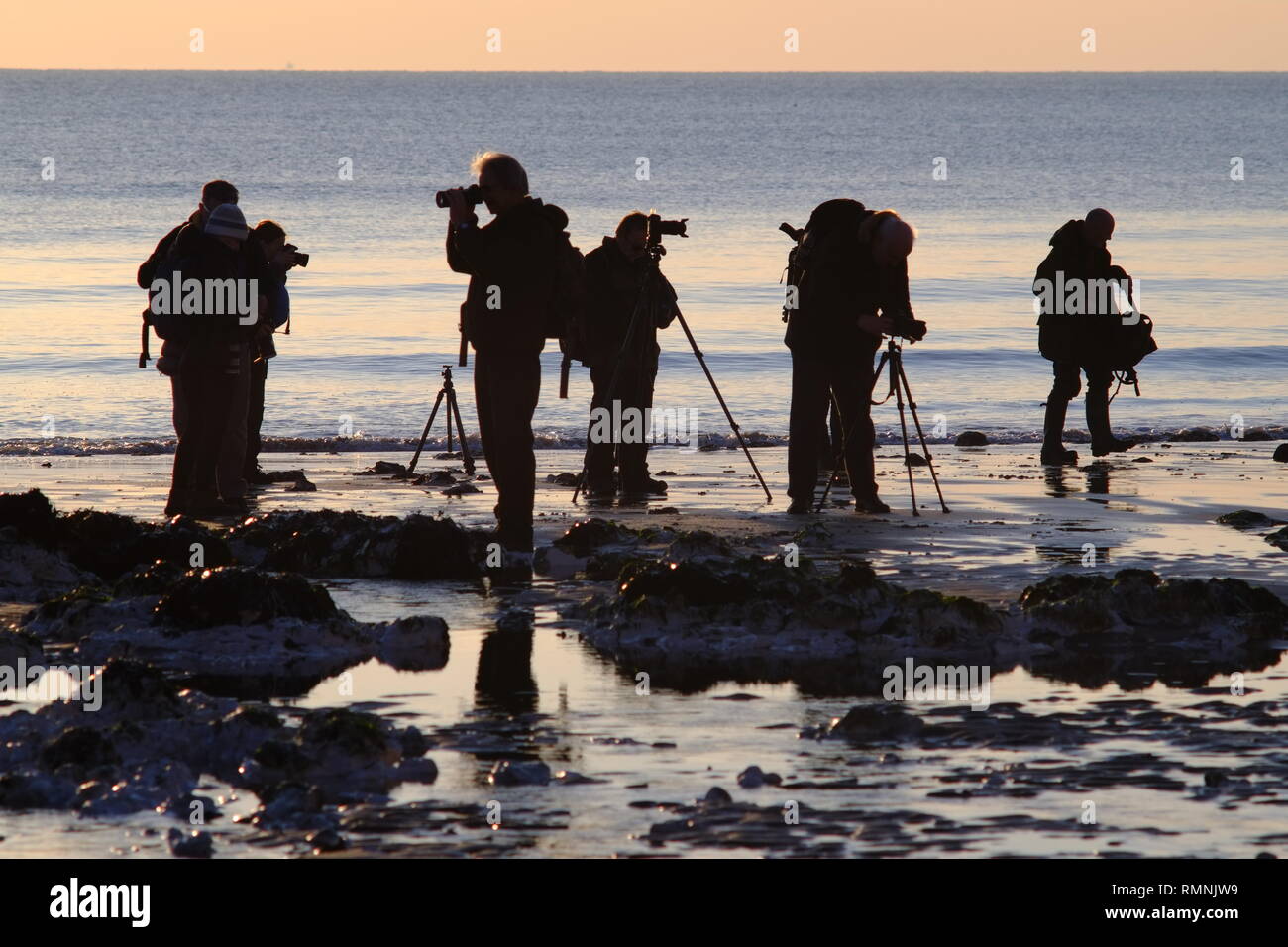 Gruppe von hobbyfotografen Fotografieren der Sonnenuntergang am Strand. Stockfoto