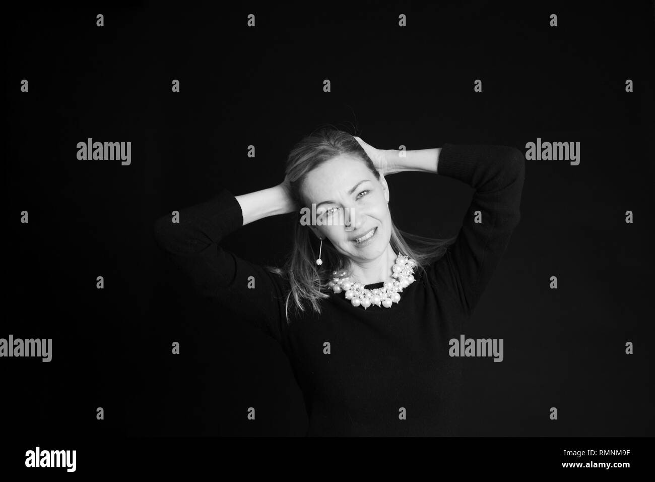 In der Nähe von Studio Portrait einer schönen Frau im schwarzen Kleid auf schwarzem Hintergrund Stockfoto